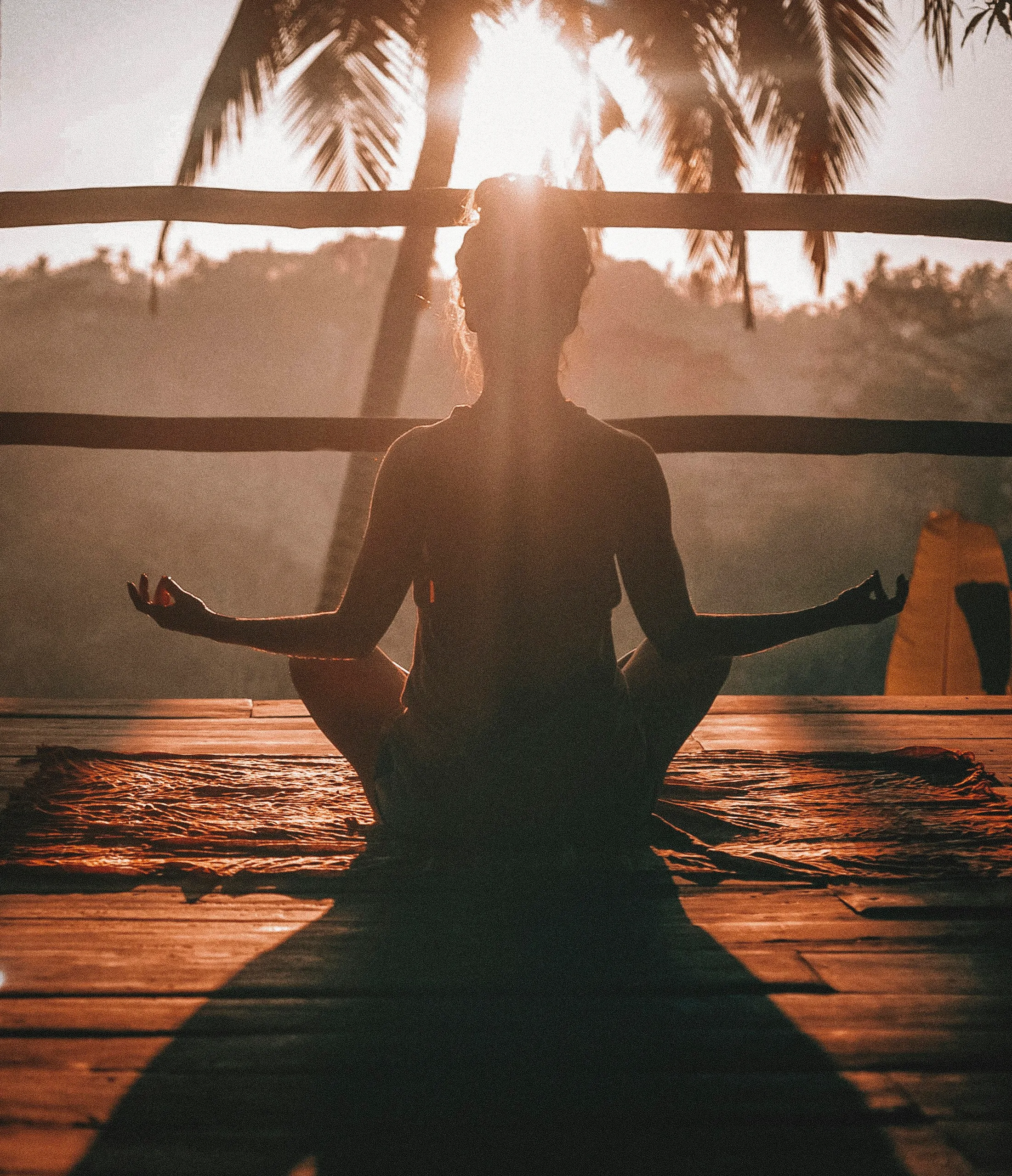 Vrouw in meditatiehouding op een houten vlonder in warm licht